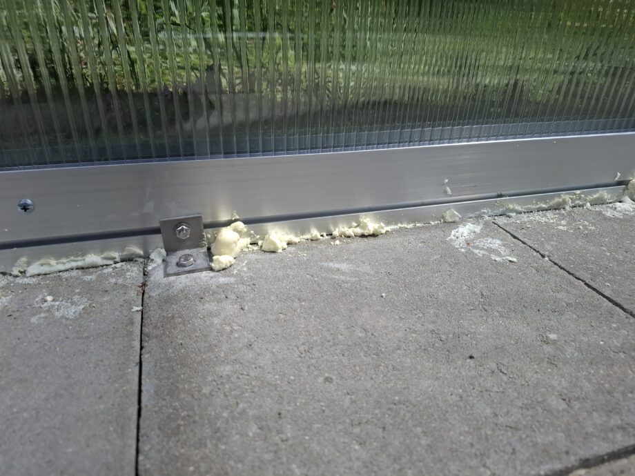 Gewächshaus im Boden verankern, in dem man es mit Winkeln verschraubt